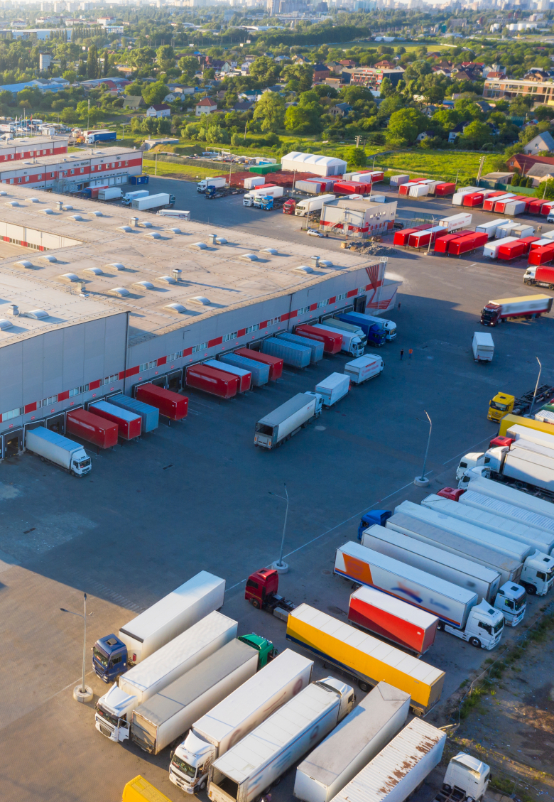 Logistics park with warehouse. Semi-trailers trucks standing on car parking and waiting for loading and unloading goods at ramps. Aerial view