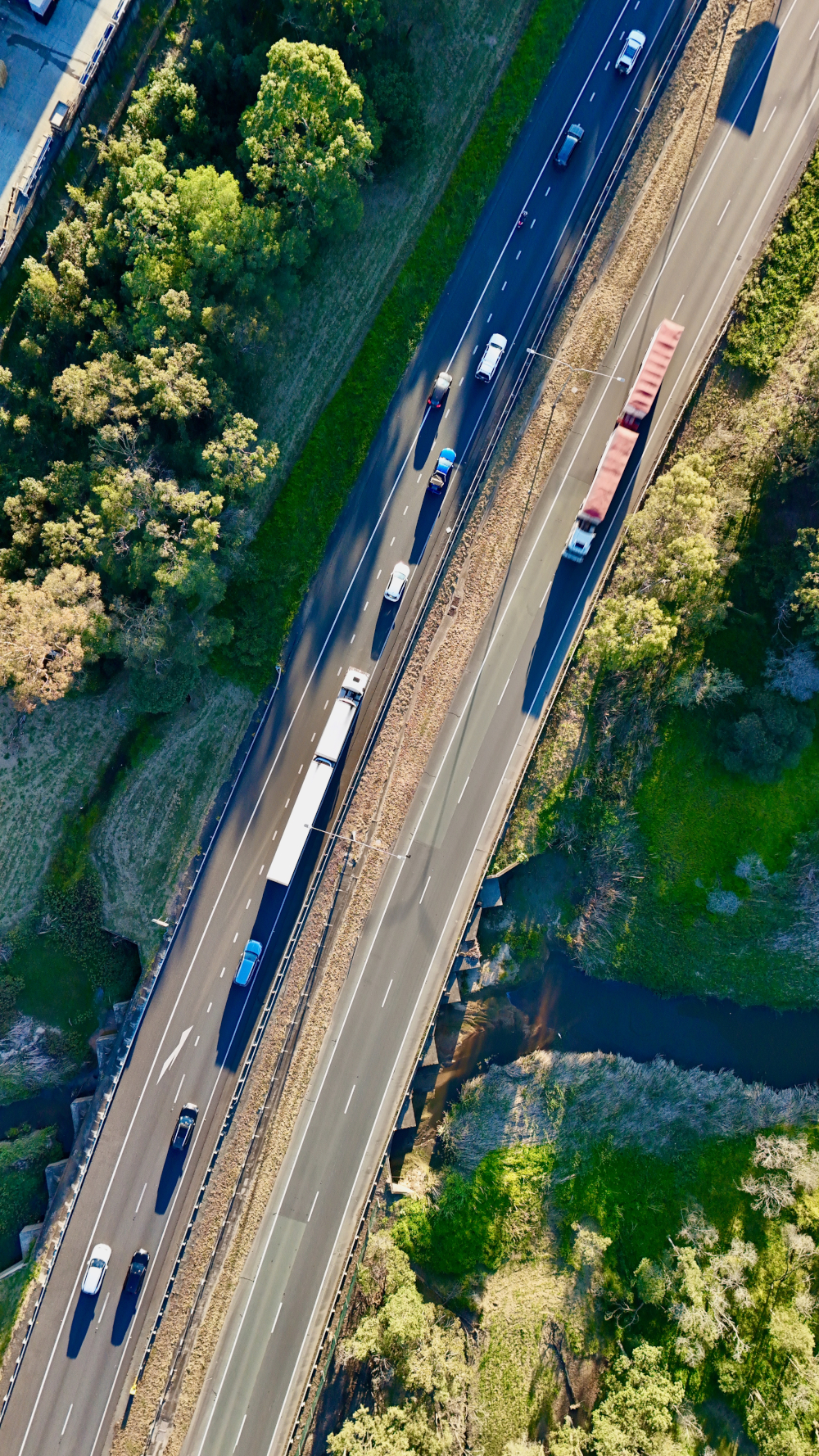 Logan Motorway, Carole Park, South Brisbane, Queensland, Australia – Aerial Image of Multi-Lane Freeway, Vehicles, Trucks, Overpass, and Adjacent Greenbelt and Creek Infrastructure